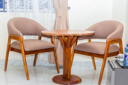 Teak armchairs and a round table in a Moonlight Hotel room